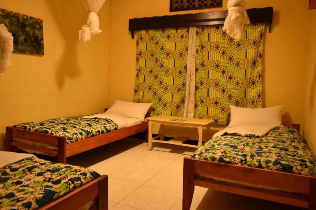 a room with two beds and a window at Room in BB - Amahoro Guest House - Triple Room with Shared Bathroom in Ruhengeri