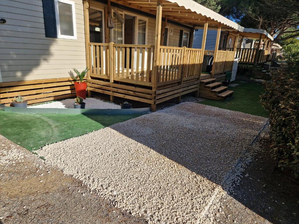 a house with a wooden deck and a porch at Camping Mar Estang in Canet-en-Roussillon