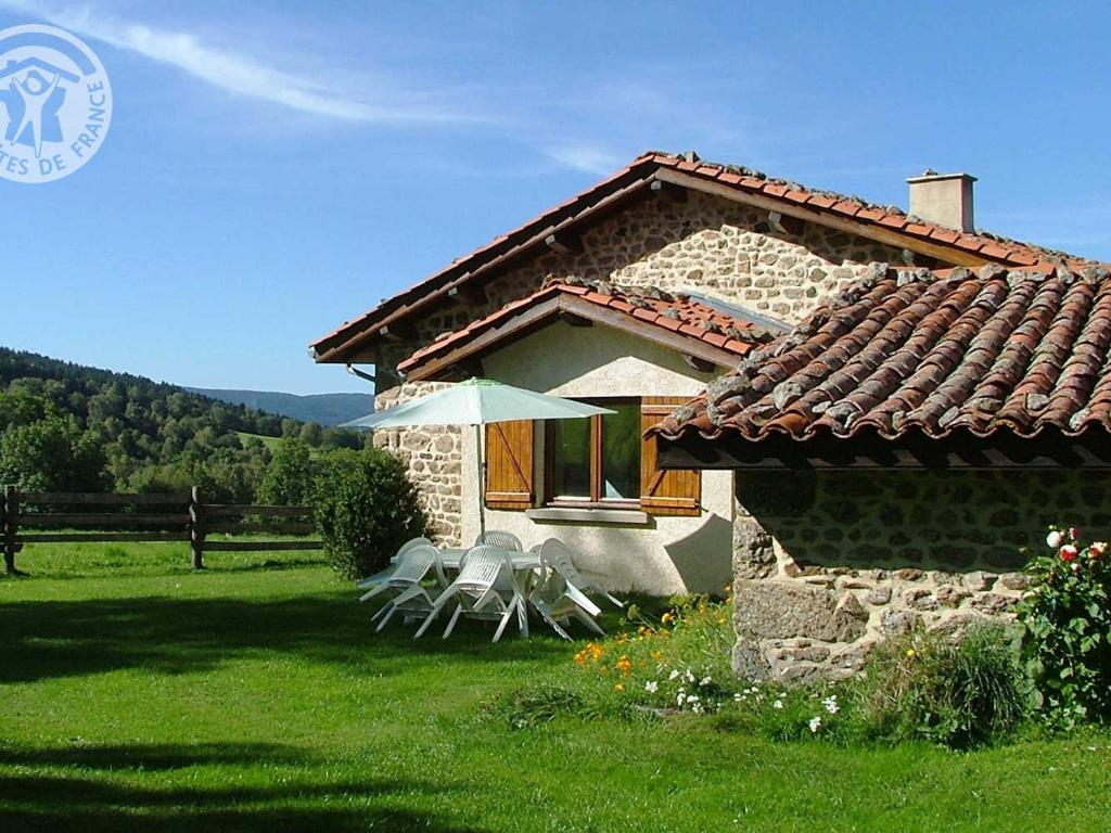 a house with two chairs and an umbrella in a yard at Gîte Sauvain, 4 pièces, 6 personnes - FR-1-496-42 in Sauvain