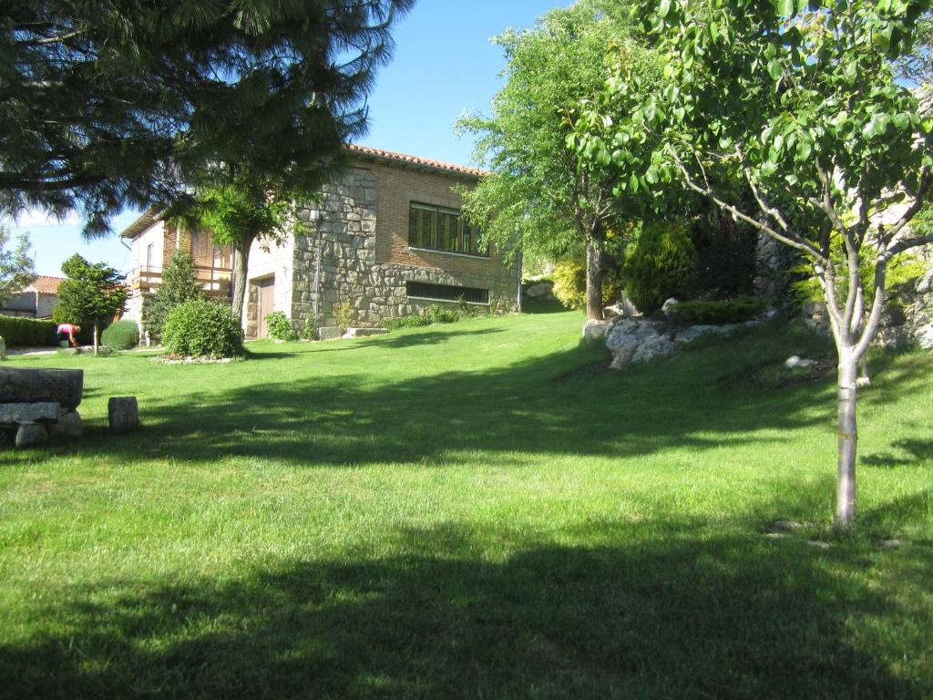 una casa en un patio con un árbol en el césped en La Ladera, en Hoyos del Espino