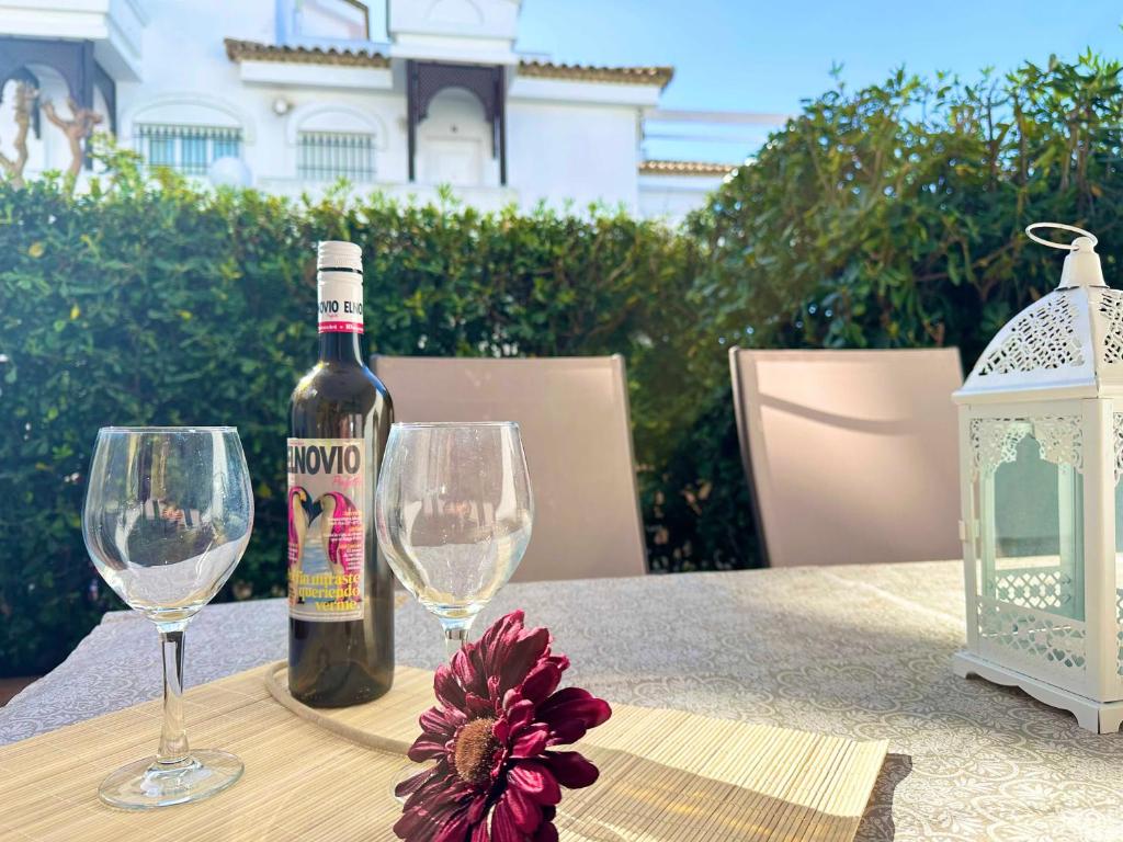 Una botella de vino y dos copas en una mesa. en Novo Sancti Petri Atardecer Planta baja en Chiclana de la Frontera