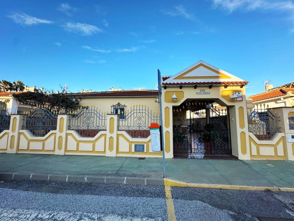 ein gelbes Gebäude mit einem Tor davor in der Unterkunft Villa Pepita - 3 dormitorios - 350 metros playa - Piscina in Torremolinos