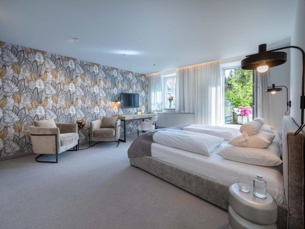 a bedroom with a large bed and a desk and chairs at Hotel Forstinger - Boutique Hotel Schärding in Schärding