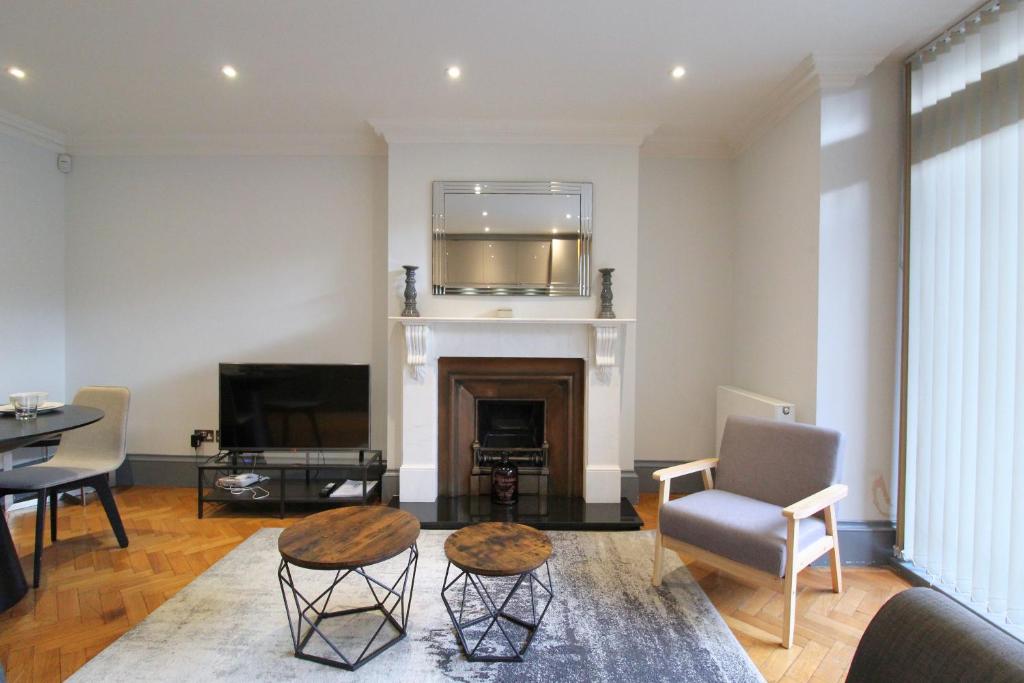 a living room with a fireplace and a tv at Barons Court Queens Club by Viridian Apartments in London