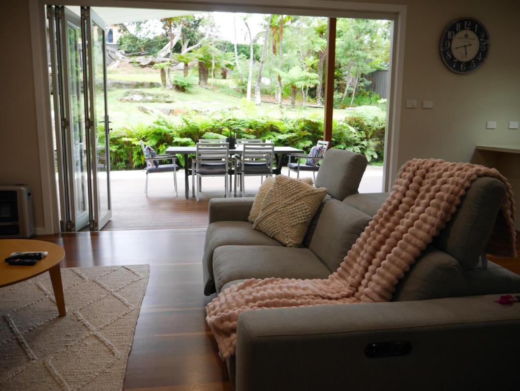 een woonkamer met een bank en een tafel en stoelen bij Luxury Home in Yowie Bay in Miranda
