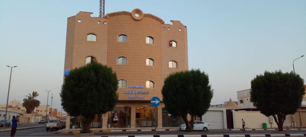 un gran edificio de ladrillo con un reloj. en شقق مساكن ابيات للشقق المخدومة, en Al Rass