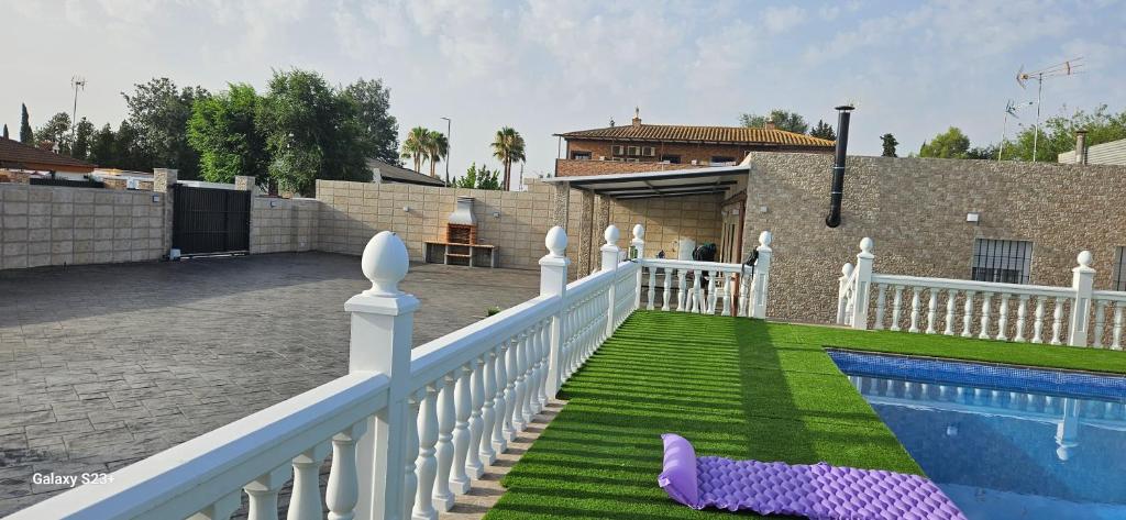 una casa con una valla blanca y una piscina en chalet El campillo en Sevilla