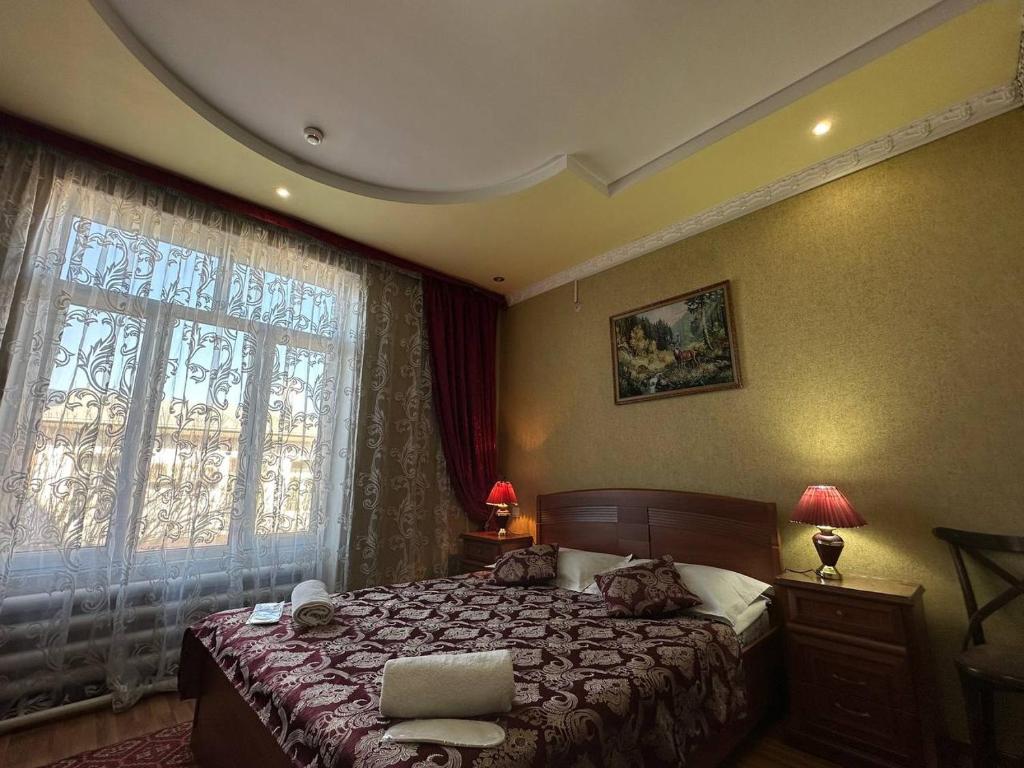 een slaapkamer met een bed en een groot raam bij Grand Canyon Hotel in Tasjkent