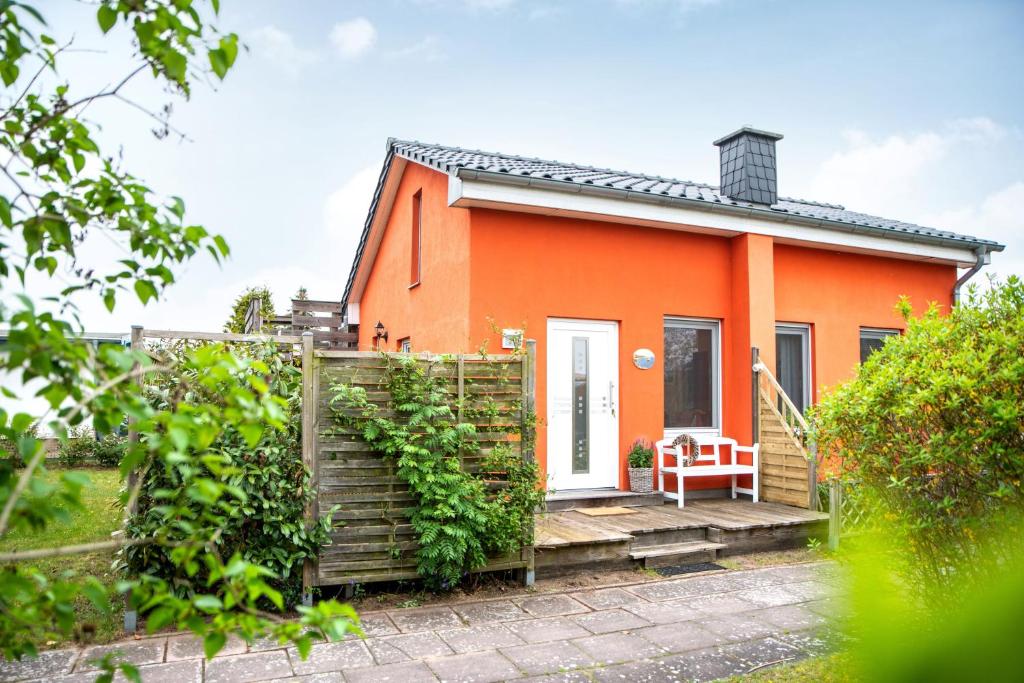 an orange house with a gate and a bench at Ferienhaus "Inselblick" 3 Sterne mit WLAN in Mönkebude