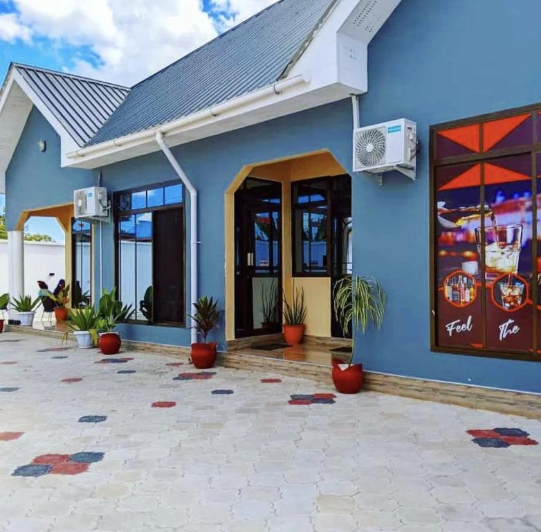 un bâtiment bleu avec des plantes devant lui dans l'établissement Rest Inn Lounge & Lodge, à Dar es Salaam