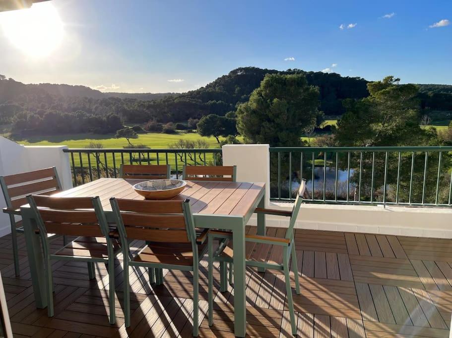 una mesa de madera y sillas en una terraza con vistas en Appartement vue sur golf Son Parc Menorca, en Son Parc