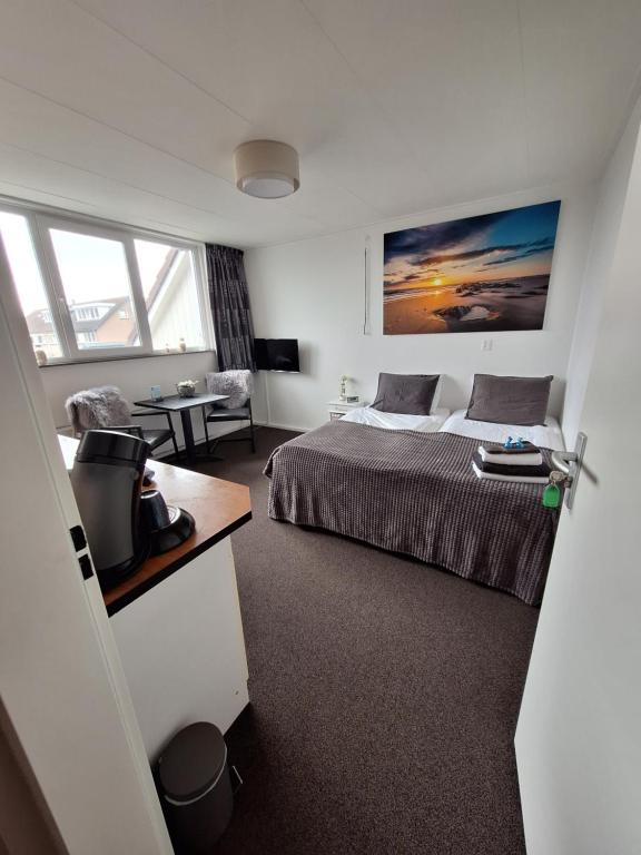 ein Schlafzimmer mit einem Bett und einem Tisch in einem Zimmer in der Unterkunft B&B Marijke in De Koog