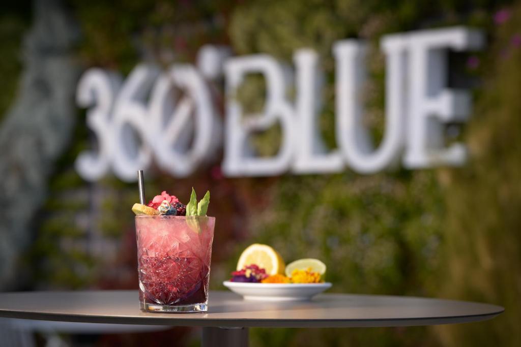 a drink sitting on a table with a plate of fruit at Óbal Hotel Marbella in Marbella