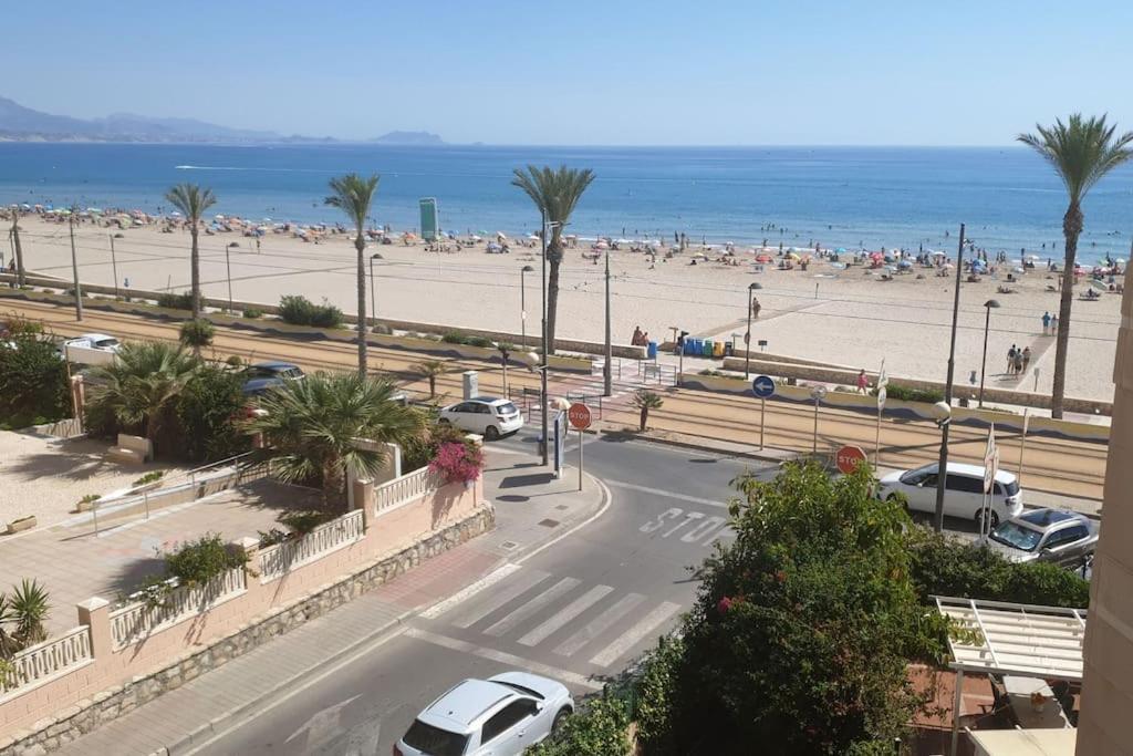 uma vista para uma praia com carros estacionados na estrada em Magnifico apartamento en primera linea de Playa em El Campello