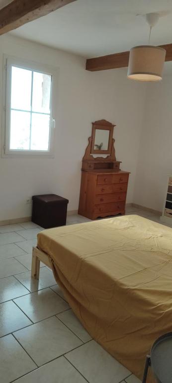 a bedroom with a bed and a dresser and a window at Les garrigues 1er étage in Pernes-les-Fontaines