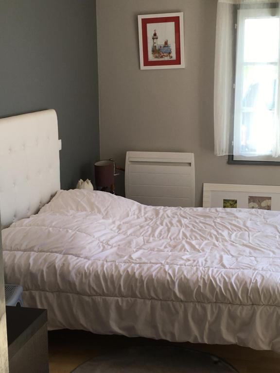 1 dormitorio con cama blanca y ventana en Chambre grise en Barbâtre