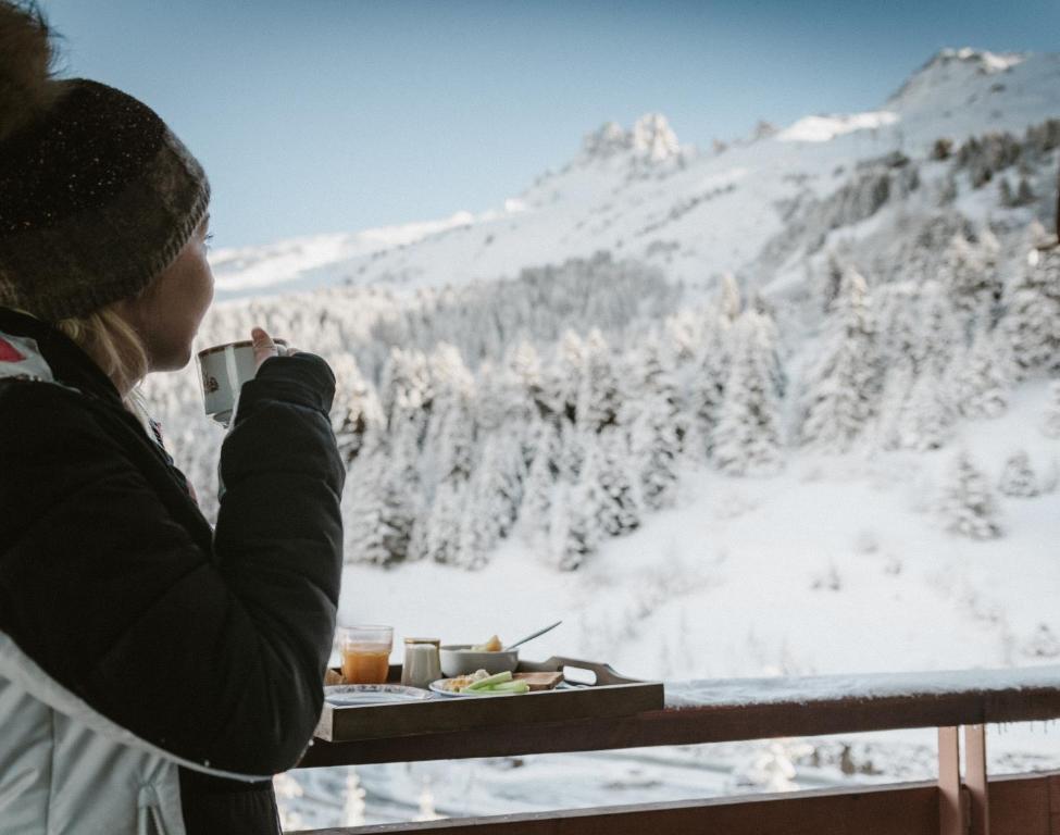 a woman taking a picture of the snow covered mountains at Hôtel Alpen Ruitor in Méribel