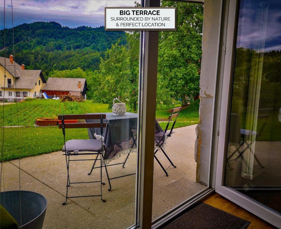eine Glastür mit einem Tisch und Stühlen auf einer Terrasse in der Unterkunft Apartments Žnidar in Spodnje Gorje