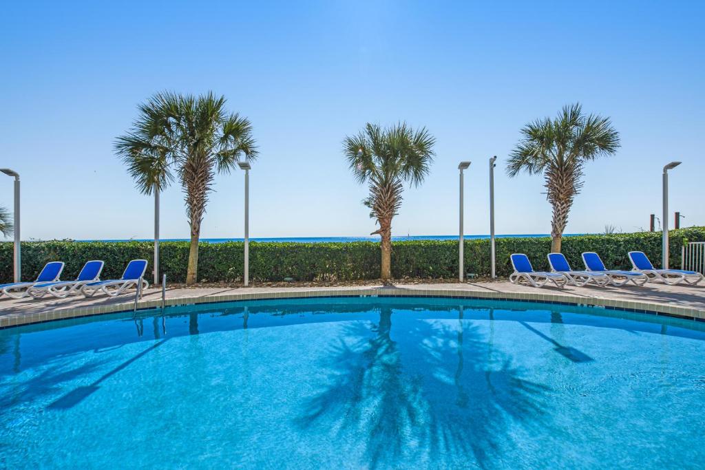 a swimming pool with chairs and palm trees at Oceanfront ,Modern, Luxury, Carolinian Resort in Myrtle Beach
