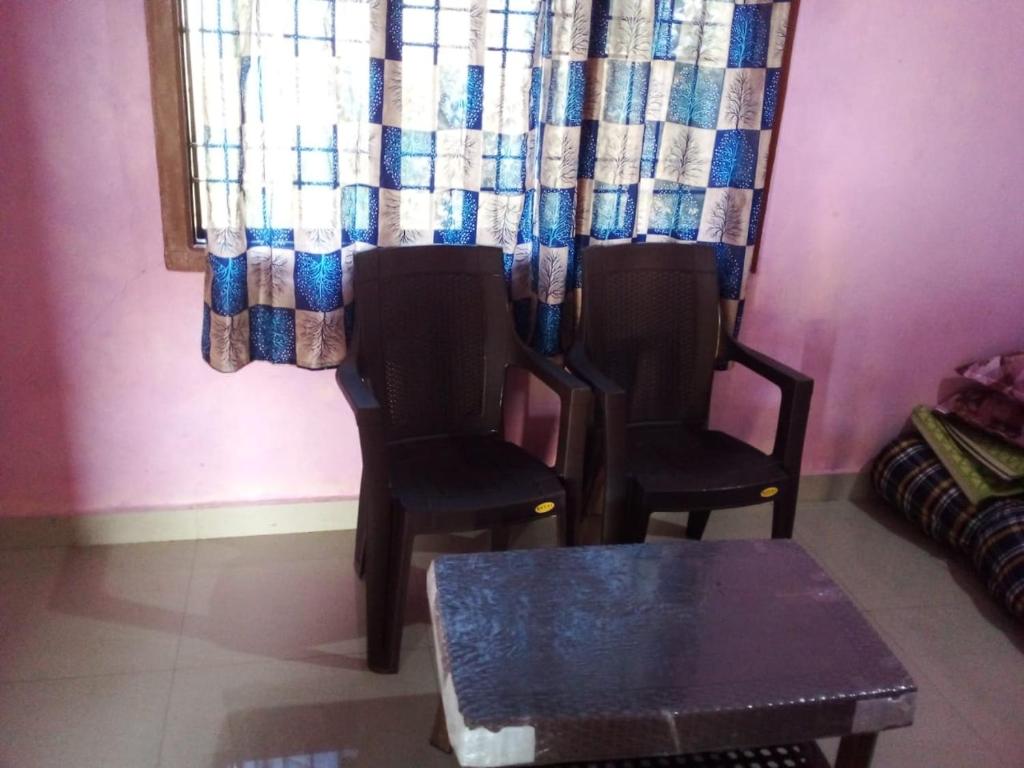 - 2 chaises et une table dans une chambre avec rideau dans l'établissement Honnavar homestays, à Honāvar