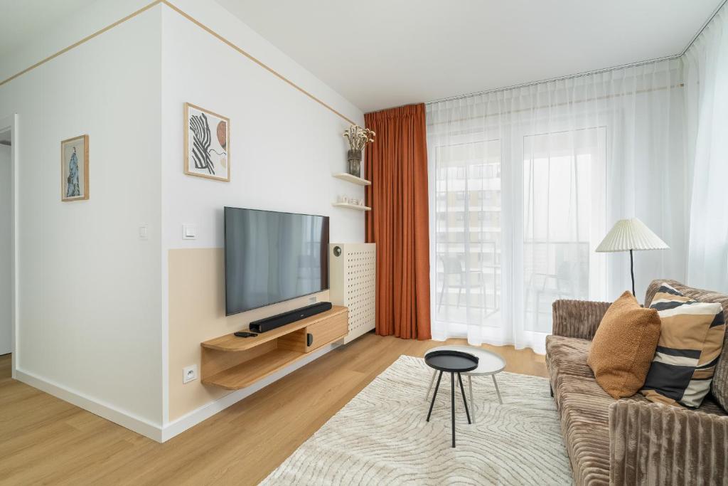 a living room with a couch and a flat screen tv at Unique 2-Bedroom Apartment on the 10th Floor with FREE GARAGE Poznań by Renters in Poznań