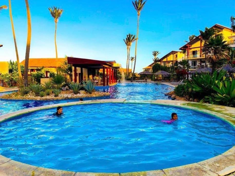 2 persone che nuotano in una piscina in un resort di Casa em resort na Taiba a São Gonçalo do Amarante