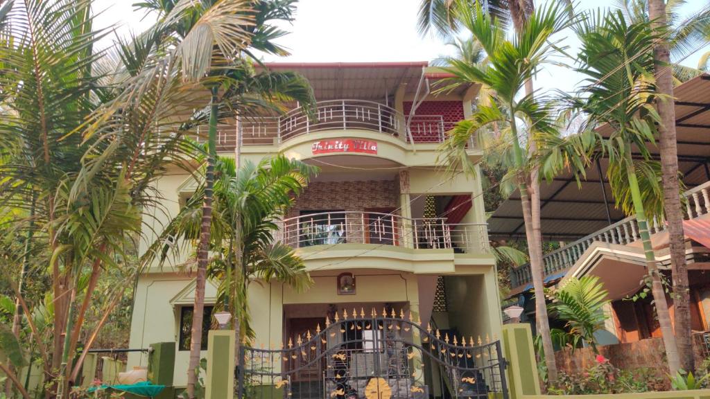 um edifício com palmeiras em frente em Trinity Villa - Home Stay em Honāvar