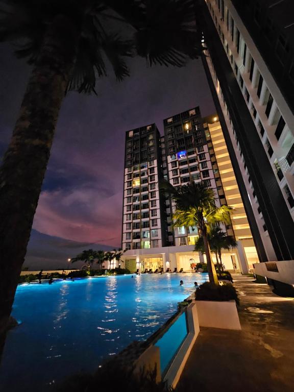 a hotel swimming pool at night with a tall building at Metropol Serviced Apartment Bukit Mertajam Perda in Bukit Mertajam