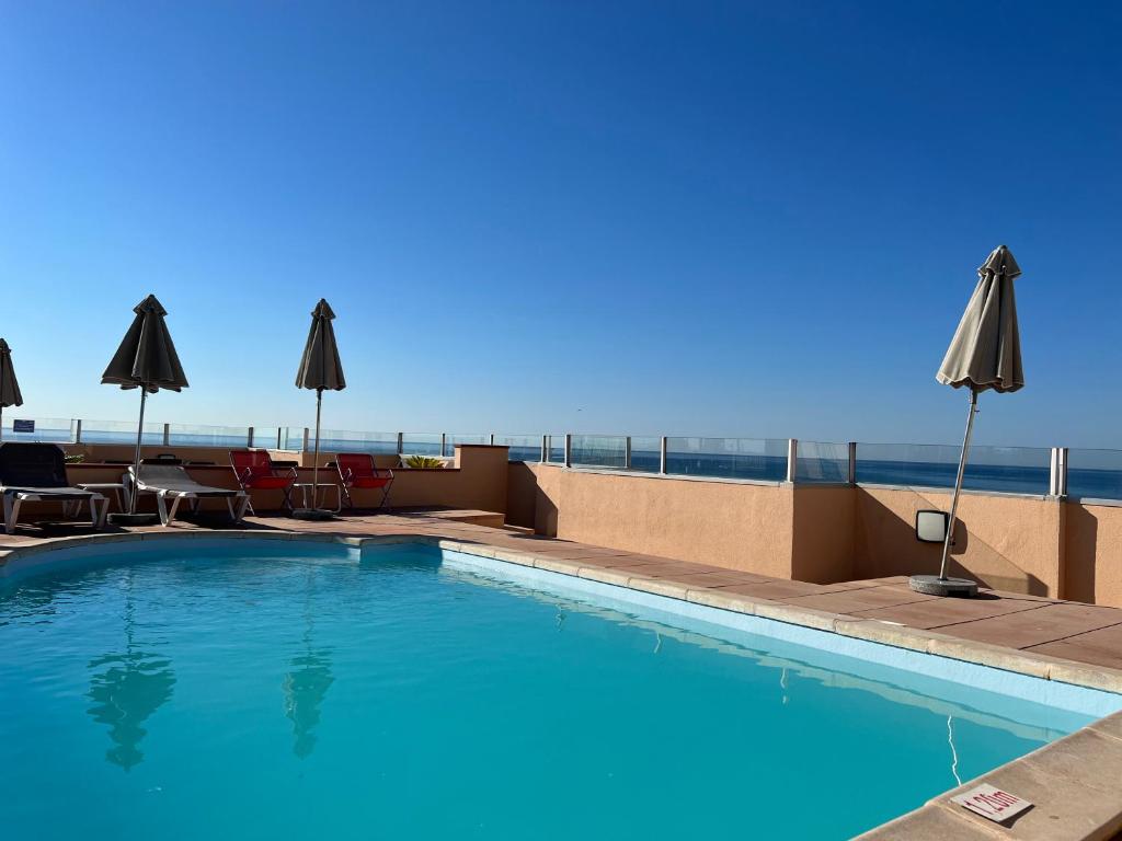 een zwembad op het dak van een hotel met parasols bij Hotel Port Marine in Sète