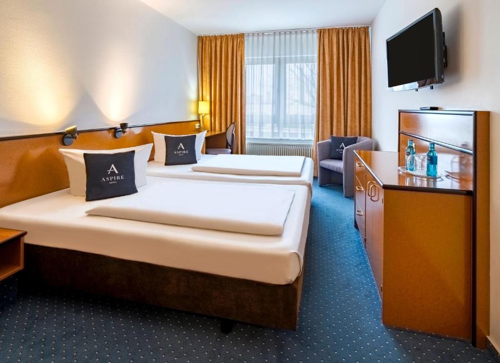 a hotel room with two beds and a television at Aspire Frankfurt Airport, Trademark Collection by Wyndham in Rüsselsheim