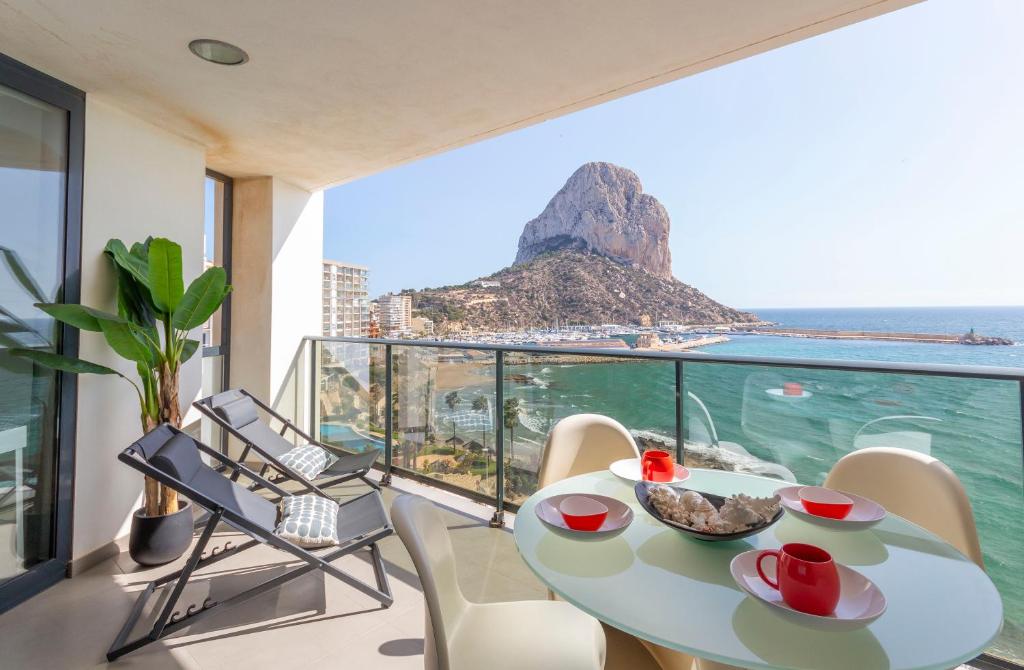 a balcony with a table and chairs and a view of the ocean at Apartamento Bernia al Mar 8A by Costa CarpeDiem in Calpe