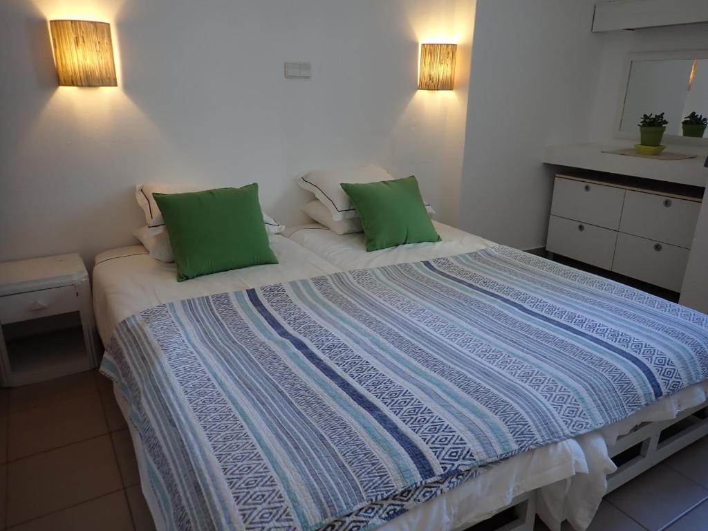 a bedroom with a large bed with two green pillows at Great value 5 mins to Praia de Rocha beach in Portimão