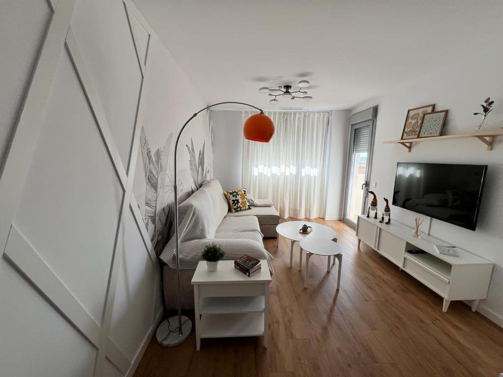 ein Wohnzimmer mit einem weißen Sofa und einem TV in der Unterkunft Jardines del Porvenir 2 in Puerto Real