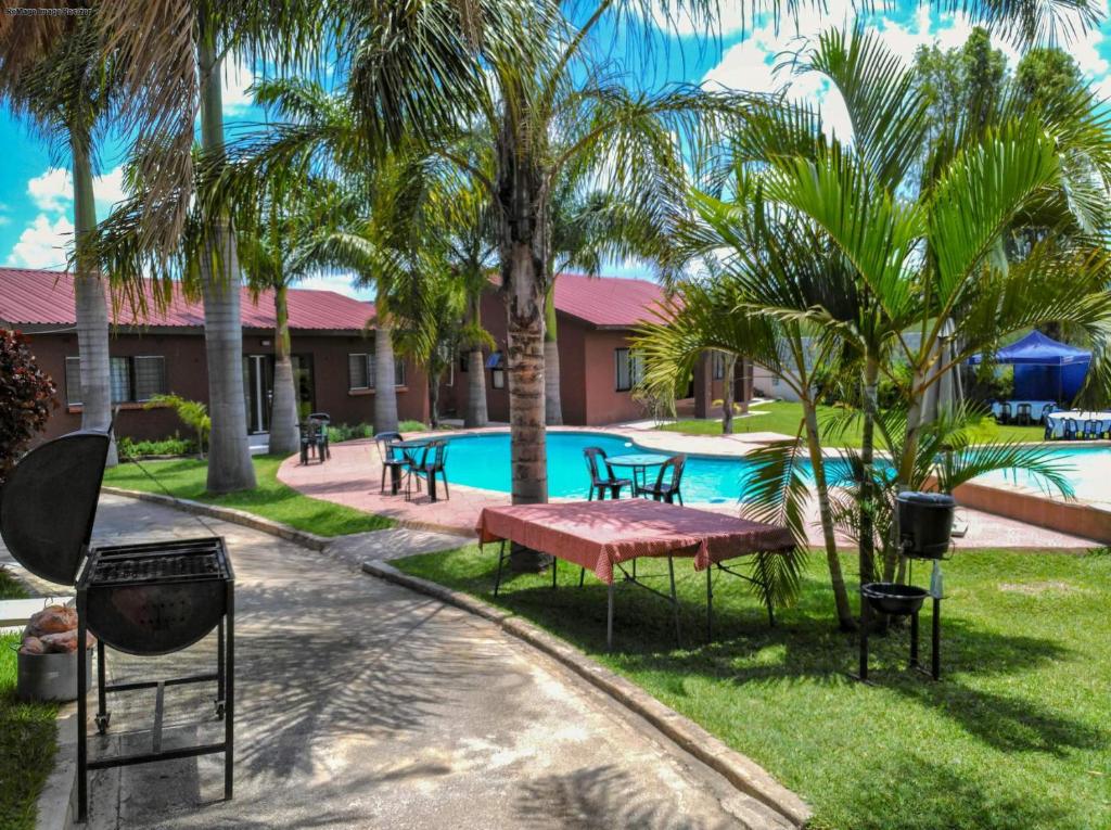 una piscina resort con una mesa de picnic y palmeras en KALIYANGILE GUEST HOUSE, en Lusaka