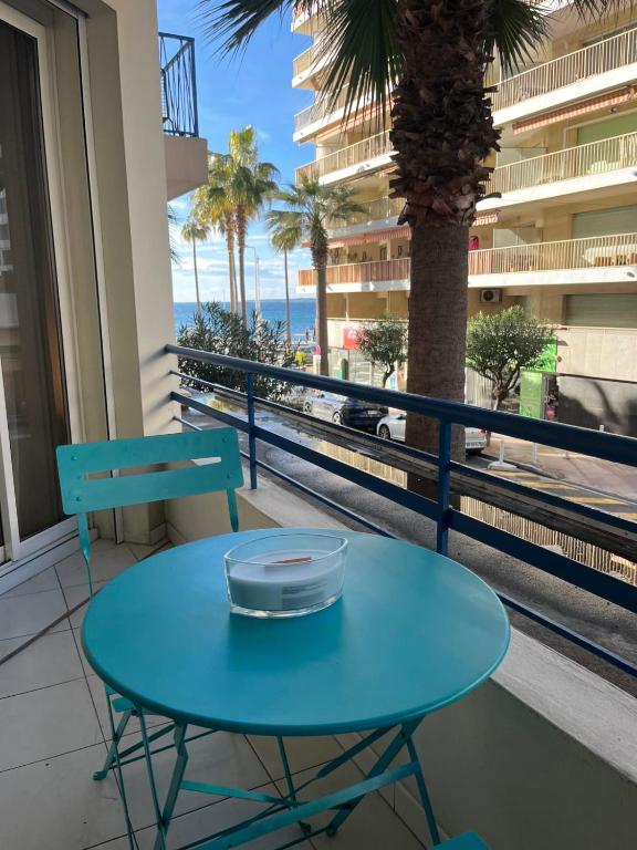 d'une table bleue et d'une chaise sur un balcon donnant sur l'océan. dans l'établissement Apartment Juan Les Pins Sea view in the heart of town with its merchants, à Antibes