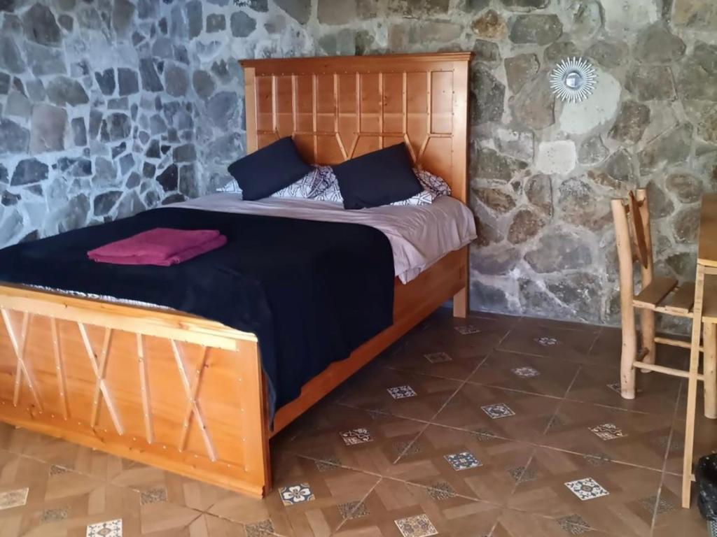 a bedroom with a bed in a stone wall at CASA TRIBU in San Antonio Palopó