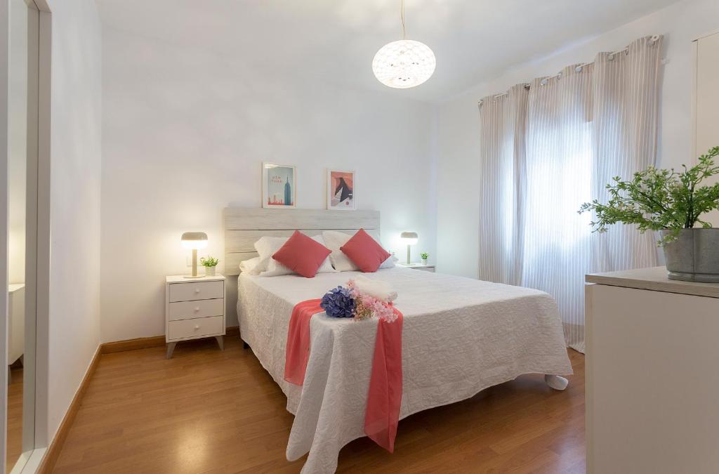 Un dormitorio blanco con una cama grande con almohadas rojas en Centrico Tranquilo 2 Rooms, en Jerez de la Frontera