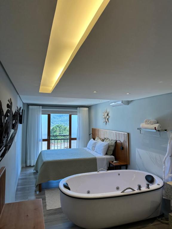 a bedroom with a bed and a bath tub in a room at Pousada Maria Monteiro Tiradentes in Tiradentes