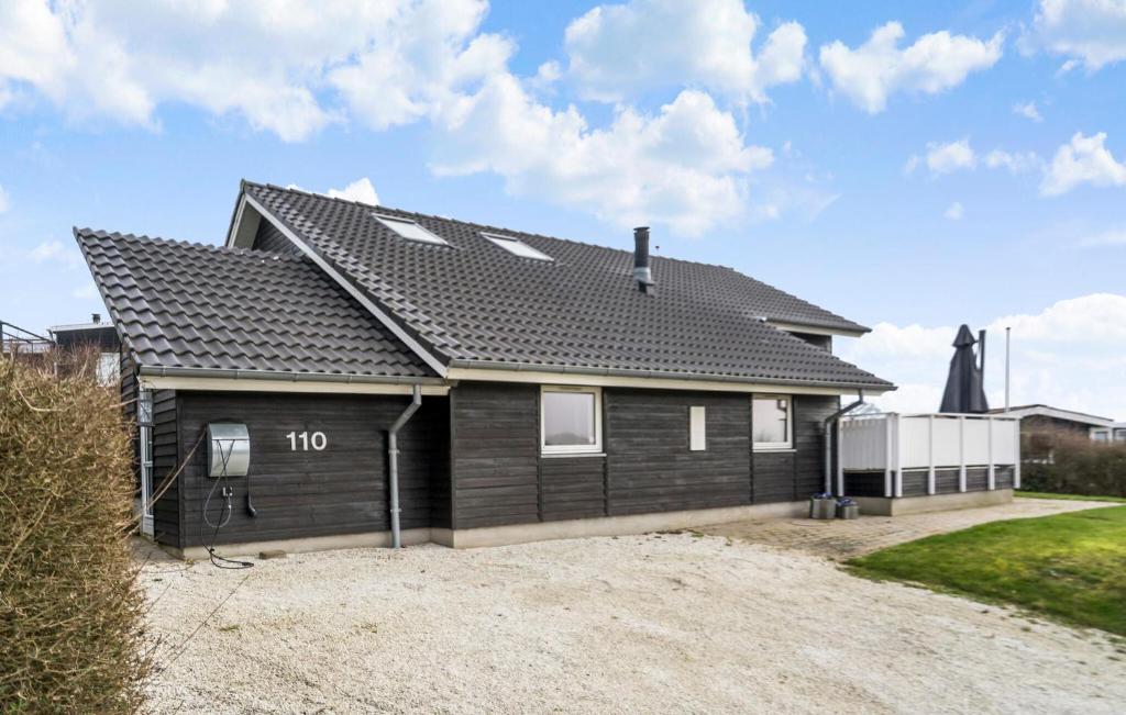 uma casa com um telhado preto numa calçada de cascalho em Amazing Home In Juelsminde With Kitchen em Sønderby