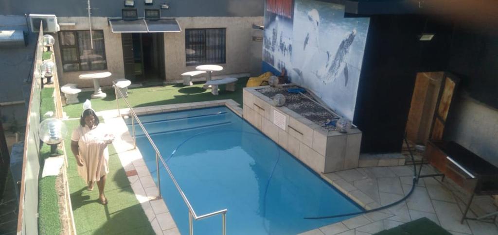 una mujer parada frente a una piscina en elim glamour hotel en Elim