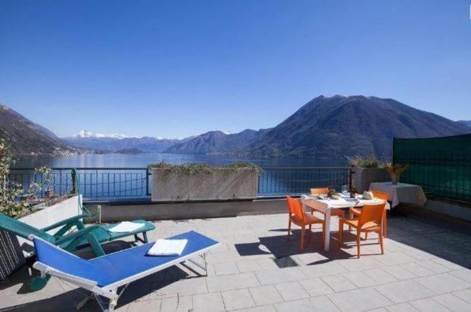 a patio with chairs and a table with a view of the water at The Little Eagle - Apartment with Terrace in Argegno