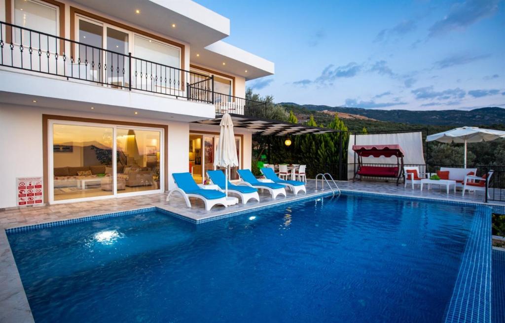 a swimming pool with chairs and a house at Villa Eslem in Kas
