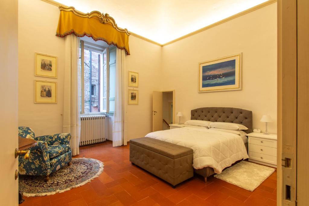 a bedroom with a bed and a chair and a window at Maggiore Suite in Perugia