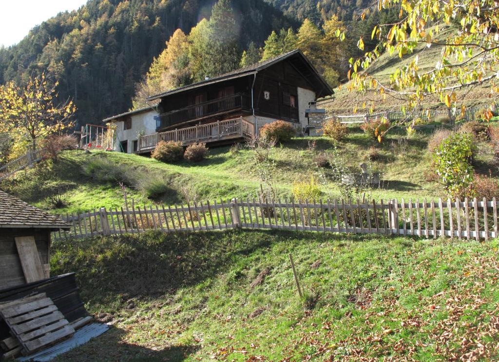 Ein altes Haus auf einem Hügel mit einem Zaun in der Unterkunft Mayen de Planraveire in Orsières