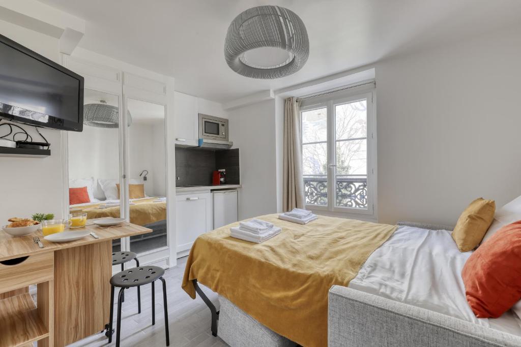 a bedroom with a bed and a desk and a tv at Branded New Cozy Studio in the Heart of Paris 17 in Paris
