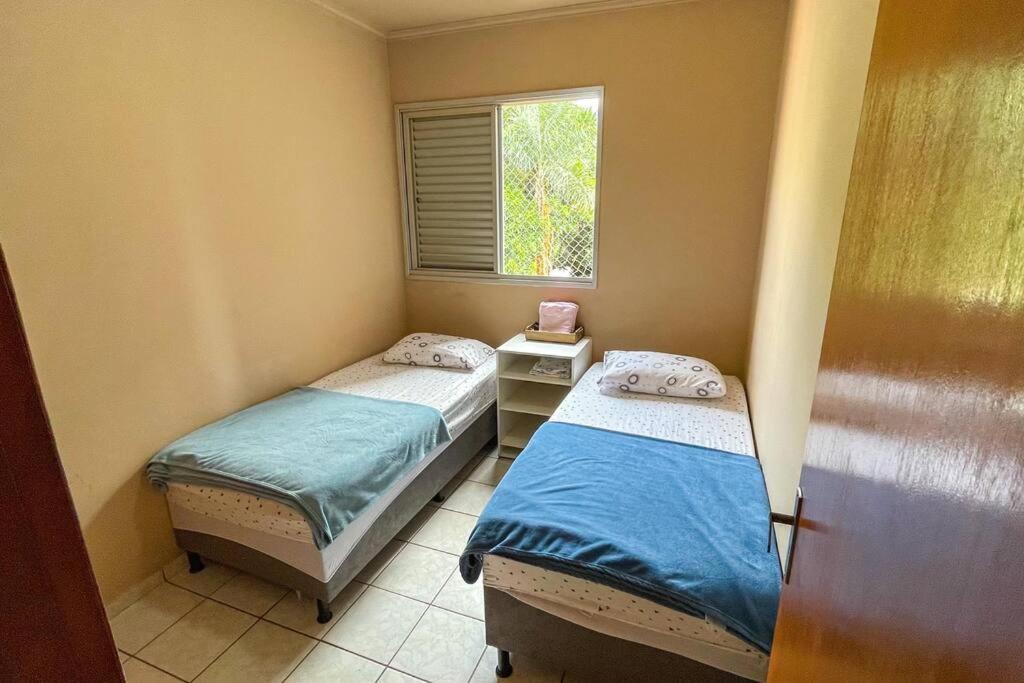 two twin beds in a room with a window at 3 Quartos da UFU in Uberlândia