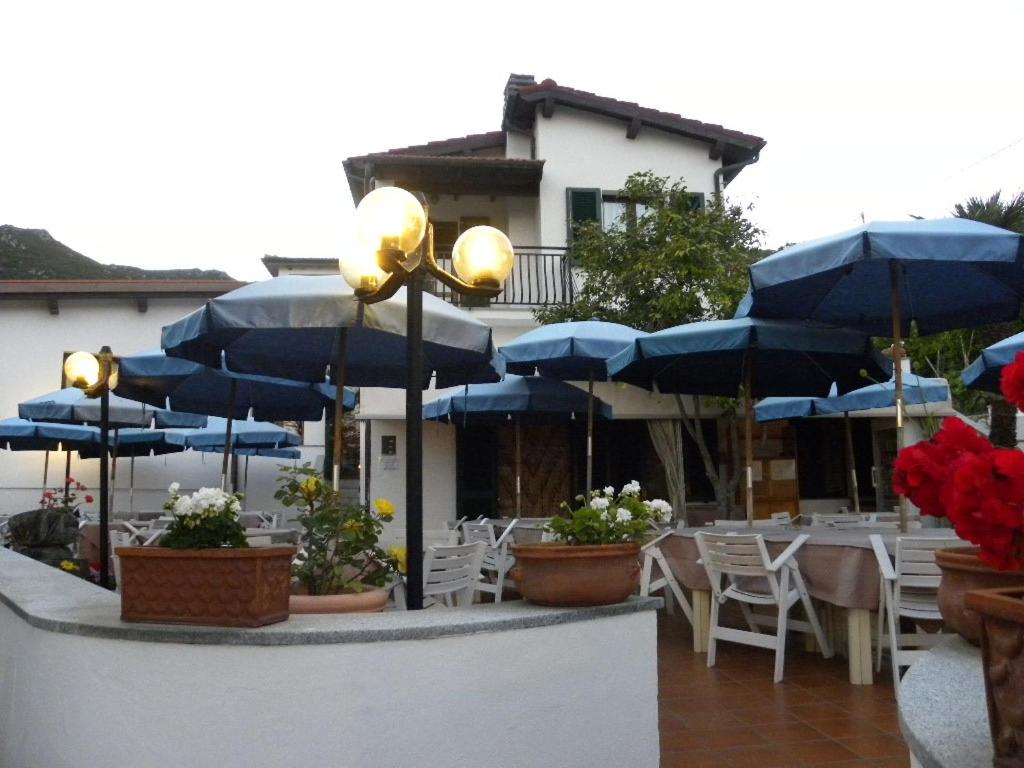 un patio con ombrelloni, tavoli e sedie blu di Locanda dell'Amicizia a Seccheto