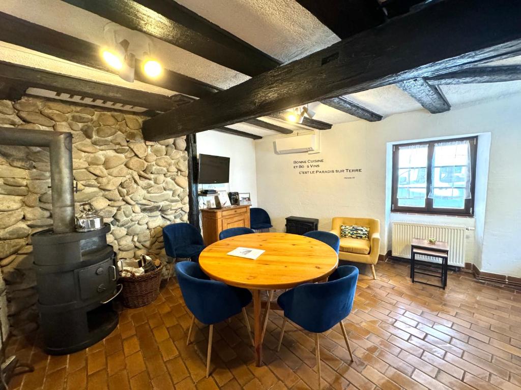 a table and chairs in a room with a stone wall at Gîte "L'Escale du Vignoble" à Ribeauville in Ribeauvillé