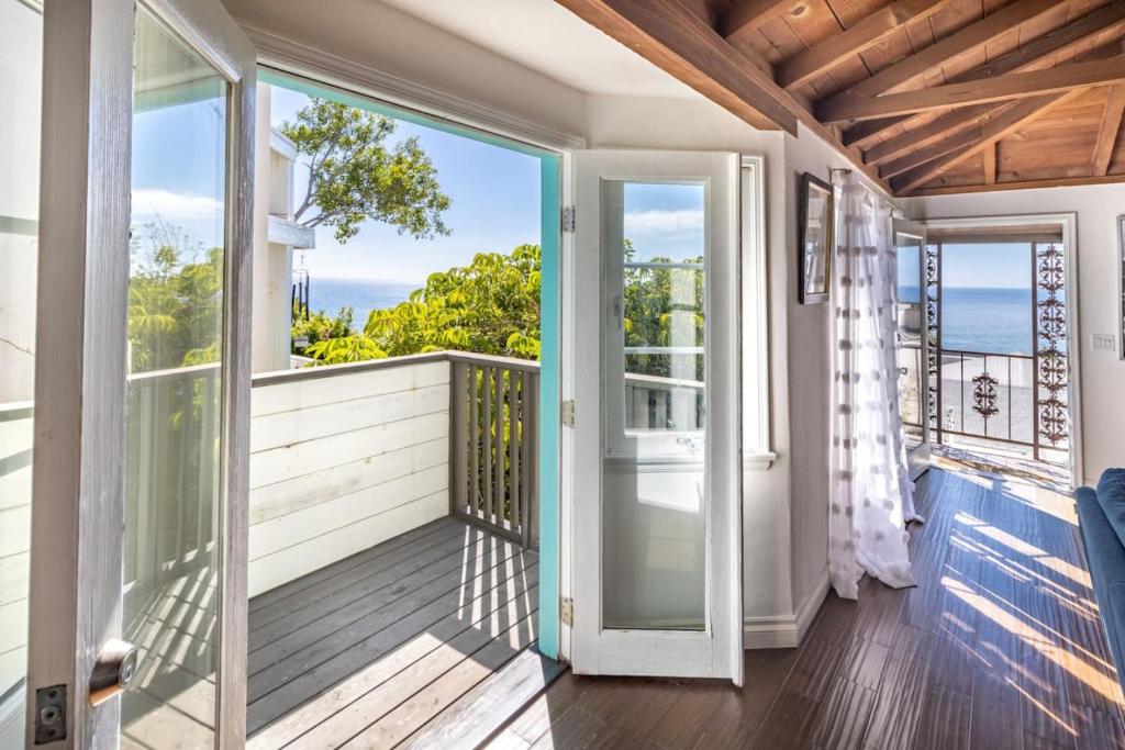 une porte ouverte s'ouvrant sur un balcon avec vue sur l'océan. dans l'établissement MAGICAL COTTAGE DIRECT OCEAN VIEW BEACH W GARAGE, YARD, FIREPLACE, à Laguna Beach