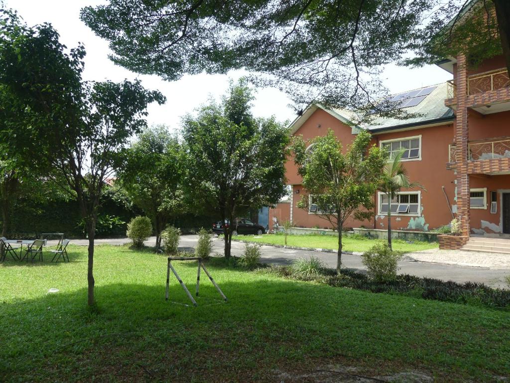 un arbre dans l'herbe devant un bâtiment dans l'établissement Templar's Court, à Port Harcourt